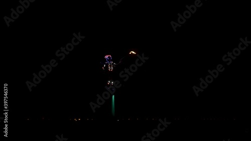 Spectacular night show on the water. A flyboarder with a flamethrower flies over the sea. photo