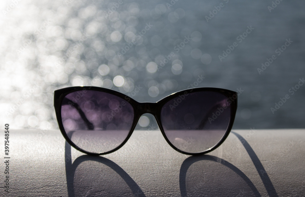 Sunglasses in the sun glare on the sea background