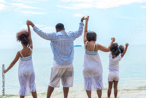 Happy African American family with African American father / asian mother and mixed race kids walking on the beach, thaliand photo