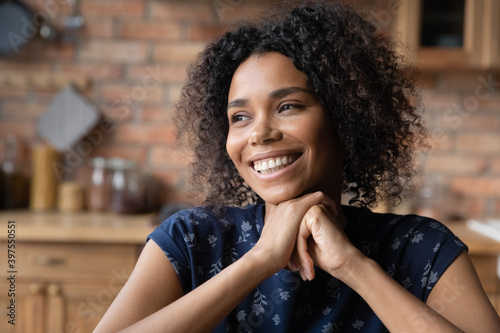 Head shot happy young pretty african american woman looking in distance, dreaming at home, remembering good life moment, visualizing future or enjoying peaceful moment indoors, vision concept.