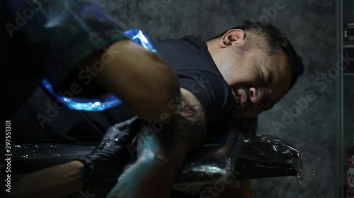 Close up shot of man face feeling pained from Tattooist making tattoo on his arm. facial expression of suffering