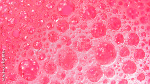Gromada różowych kropli oleju skąpana w błyszczącej pianie
