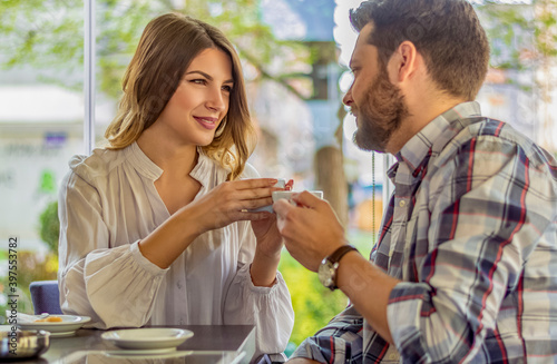 Young couple in love sitting in a cafe, drinking coffee, having a conversation and enjoying the time spent with each other.