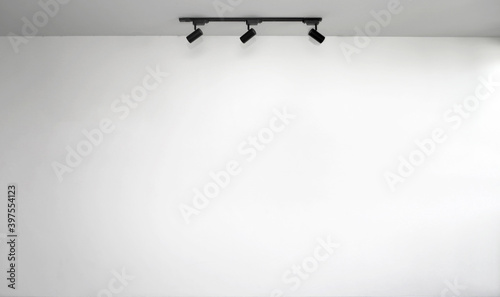 Empty white wall with ceiling light from panel bulbs.