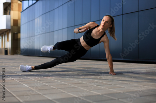 Fitness woman in sportswear doing side plank exercise outdoors.
