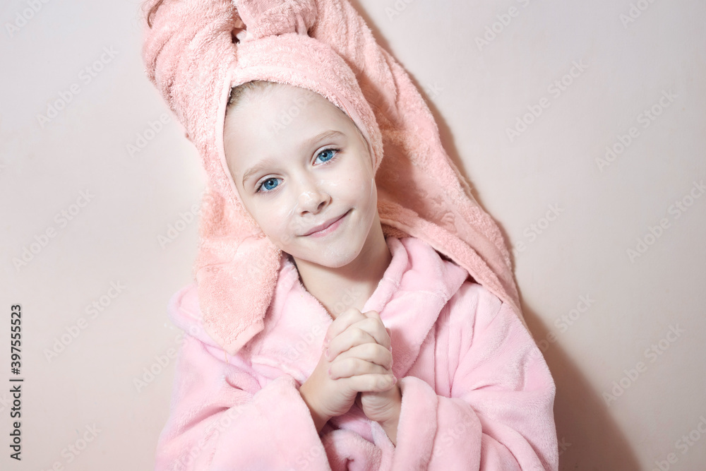 Φωτογραφία a little girl with blue eyes in a pink robe and a pink towel on her head after a bath smiles and looks into the frame