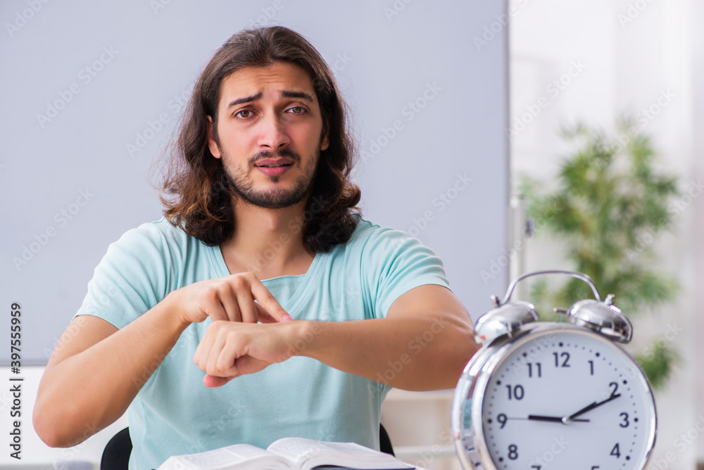 Young male student preparing for exams in time management concep Young male student preparing for exams in time management concep