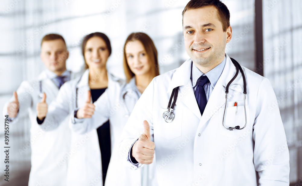 Group of professional doctors are standing as a team with thumbs up in a hospital office, ready to help their patients. Medical help, insurance in health care and medicine concept Group of professional doctors are standing as a team with thumbs up in a hospital office, ready to help their patients. Medical help, insurance in health care and medicine concept