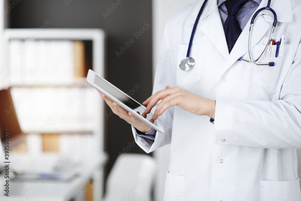 Unknown male doctor using tablet computer in sunny clinic, closeup. Perfect medical service in hospital. Medicine and healthcare concept Unknown male doctor using tablet computer in sunny clinic, closeup. Perfect medical service in hospital. Medicine and healthcare concept