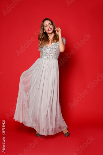 Happy woman in stylish dress on red background. Christmas party