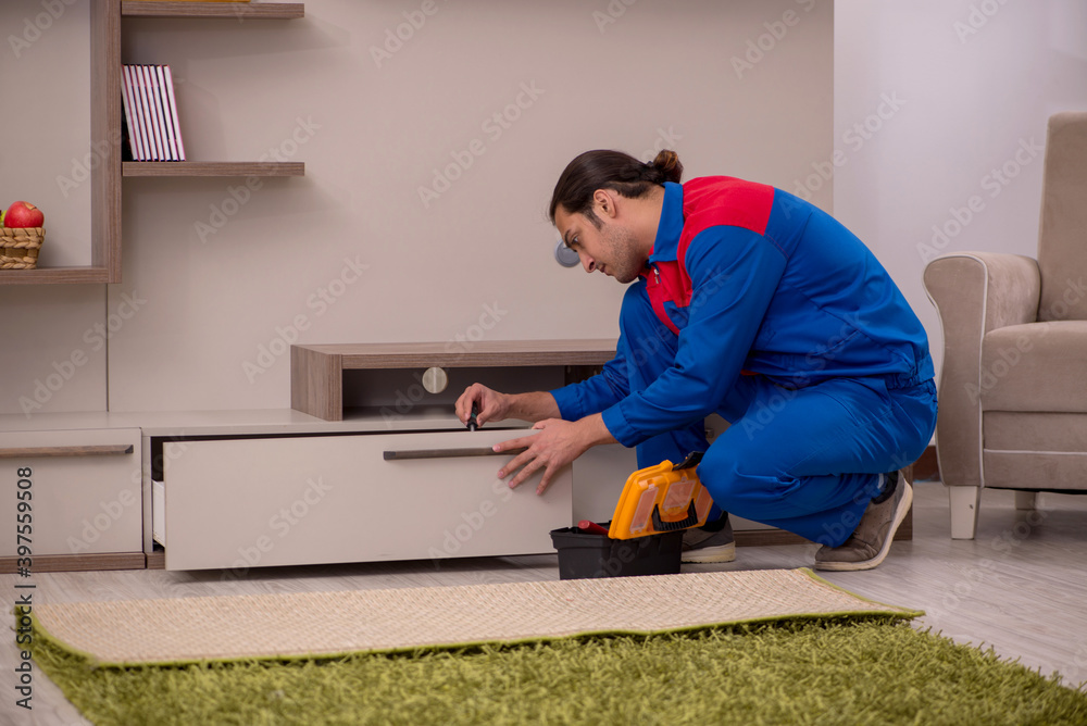 Young male contractor repairing drawyer indoors Young male contractor repairing drawyer indoors