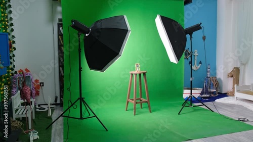 Photo or video studio with two hexagone studio lights. Hourglass on green curtain and fixed chair