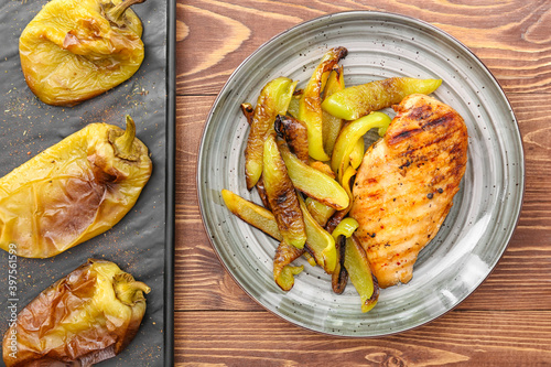 Plate with grilled bell peppers and chicken on wooden table photo