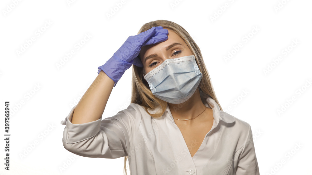 Young doctor in a medical mask is experiencing a headache at work, massaging the lobe of the head, looking at the camera. Isolated on white background. Young doctor in a medical mask is experiencing a headache at work, massaging the lobe of the head, looking at the camera. Isolated on white background.