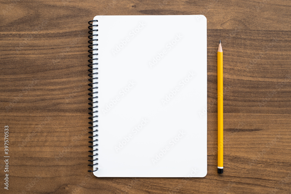 Blank notebook with pen is on top of wood office desk table. Top view, flat lay. Blank notebook with pen is on top of wood office desk table. Top view, flat lay.