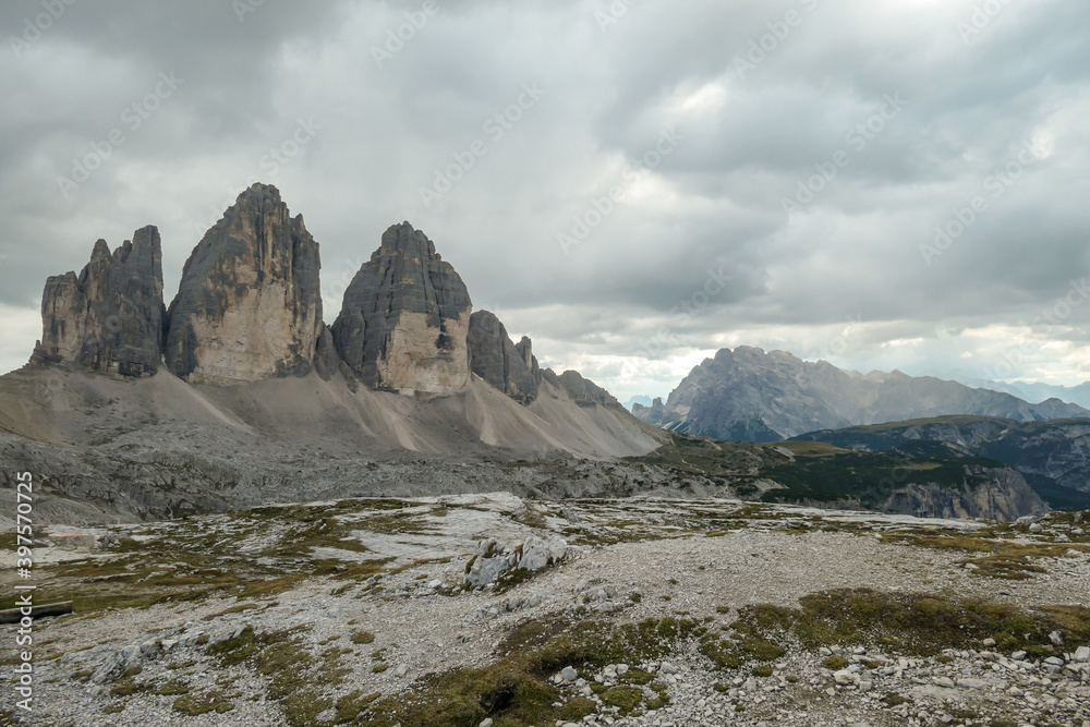 Obraz premium A panoramic capture of the famous Tre Cime di Lavaredo (Drei Zinnen) and surrounding mountains in Italian Dolomites. The mountains are surrounded by thick clouds. A lot of landslides. Serenity