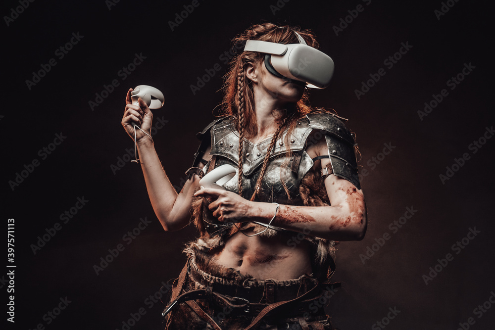 Portrait of a barbaric woman from nord dressed in medieval armour posing in dark background with virtual reality headset.