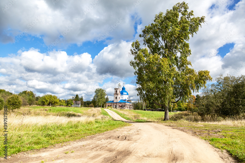 Rural landscape with orthodox church, road and birch