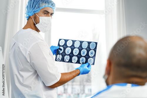 Two male doctors examine MRI brain scan of a patient in cabinet