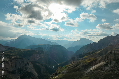 A panoramic view on a vast valley in Italian Dolomites. The valley is surrounded with high mountains from each side. There are a few clouds above. Remote and isolated place. Remedy