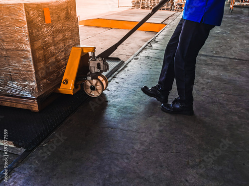 Worker driving forklift loading shipment carton boxes goods on wooden pallet at loading dock from container truck to warehouse cargo storage in freight logistics, transportation industrial, delivery