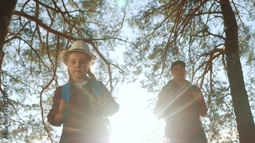 happy family with backpacks go on a trip through the park. travel kid dream adventure concept. dad and kid daughter go hiking in the park with pine tourist trees. happy family dream about adventure photo