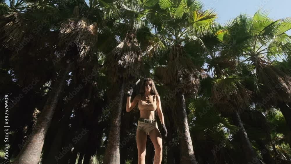 Young athletic beautiful woman in short shorts and top holding machete jumping towards to camera slow motion view. Spirit of adventure. Survivor woman concept Young athletic beautiful woman in short shorts and top holding machete jumping towards to camera slow motion view. Spirit of adventure. Survivor woman concept