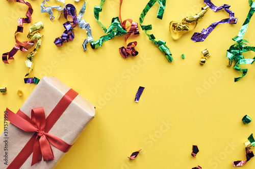 Christmas composition. Giftbox with red ribbon and confetti decorations on pastel paper colorful background. Christmas, winter, new year celebration concept. Flat lay, top view, copy space photo