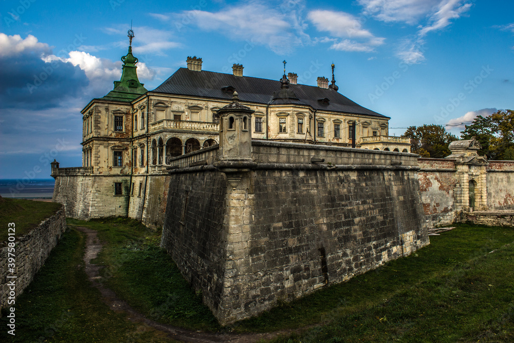 Pidhirtsi Castle. A large old estate, against the sky, with large towers.