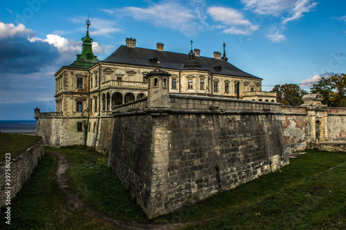 Pidhirtsi Castle. A large old estate, against the sky, with large towers.