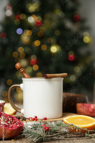 Blank white ceramic cup in festive arrangement with Christmas tree bokeh light in the background.