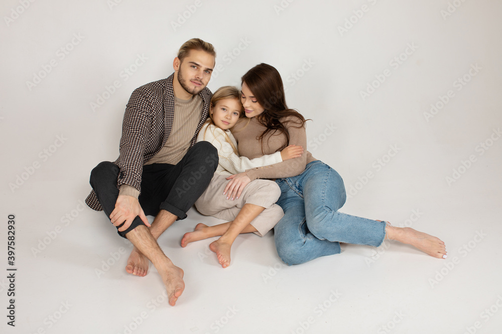 Portrait of attractive father, daughter and mother embracing together in front of grey background. Portrait of attractive father, daughter and mother embracing together in front of grey background.