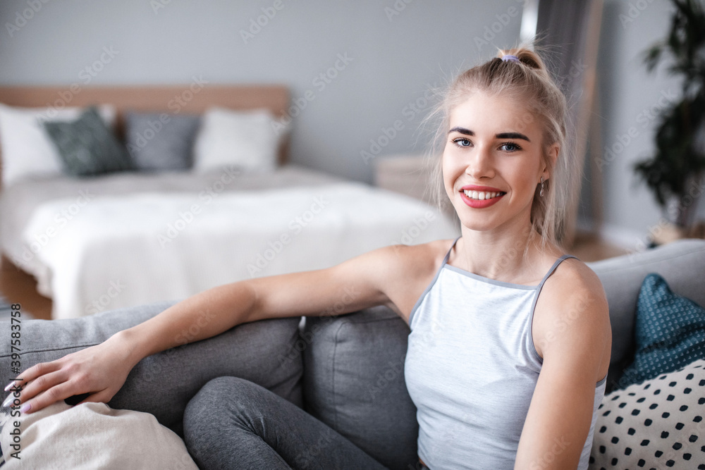 Beautiful smiling fitness woman looking at the camera and relax on the couch at home