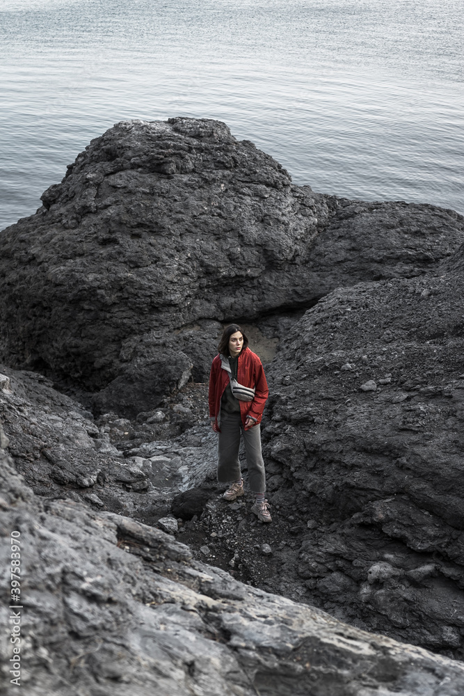 The girl makes her way through the rocky coast of the Black Sea. Novy Svet, Crimea. Clear Sunny day. Hiking, traveling, Freedom, Lifestyle concept.