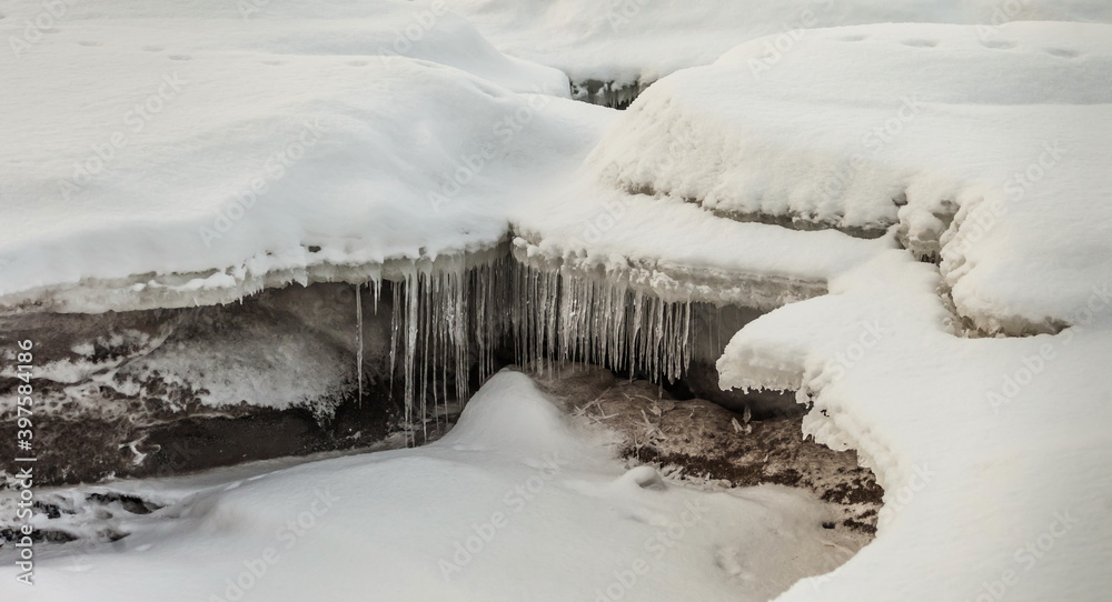 Icicles and frost on a snow-covered frozen river Icicles and frost on a snow-covered frozen river