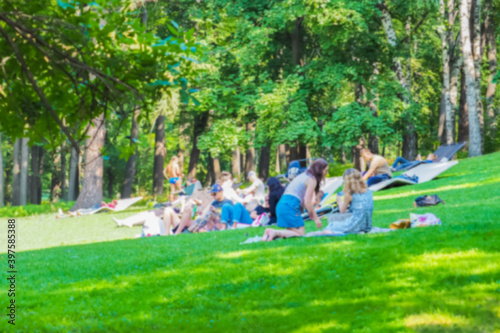 Teenagers lie on green grass. Summer vacation in the city park blurred background, picnic