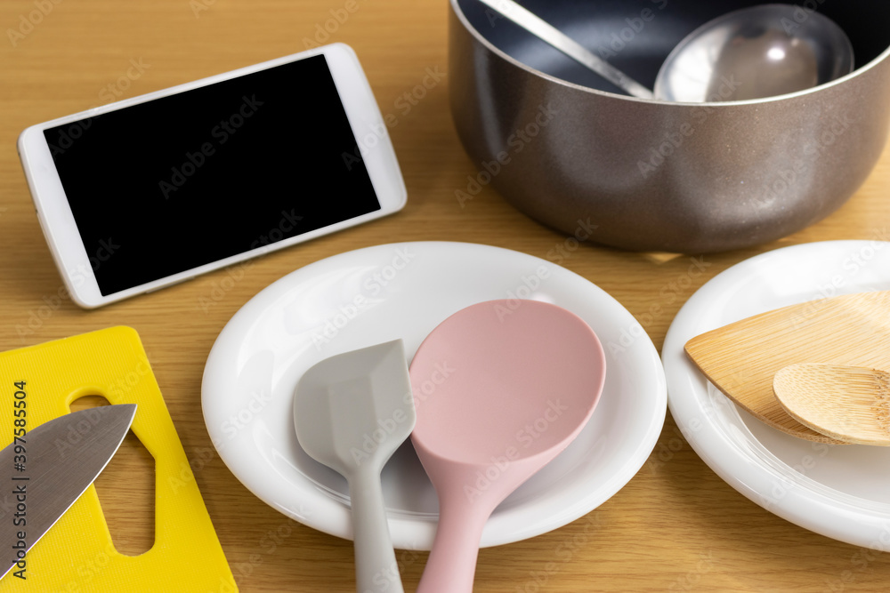スマートフォンを見ながら料理をするイメージ スマートフォンを見ながら料理をするイメージ