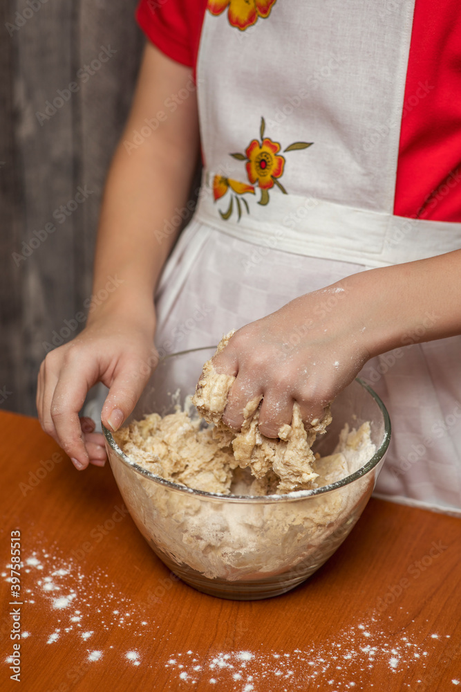 A girl in a chef's apron kneads cookie dough. Homemade baking.