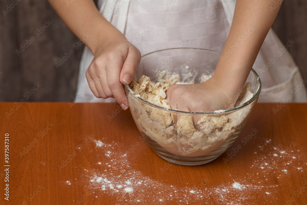 A girl in a chef's apron kneads cookie dough. Homemade baking.