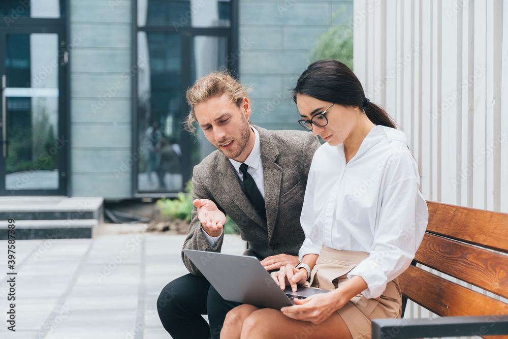 asian girl and man in business clothes on a bench with a laptop are discussing
asian girl and man in business clothes on a bench with a laptop are discussing