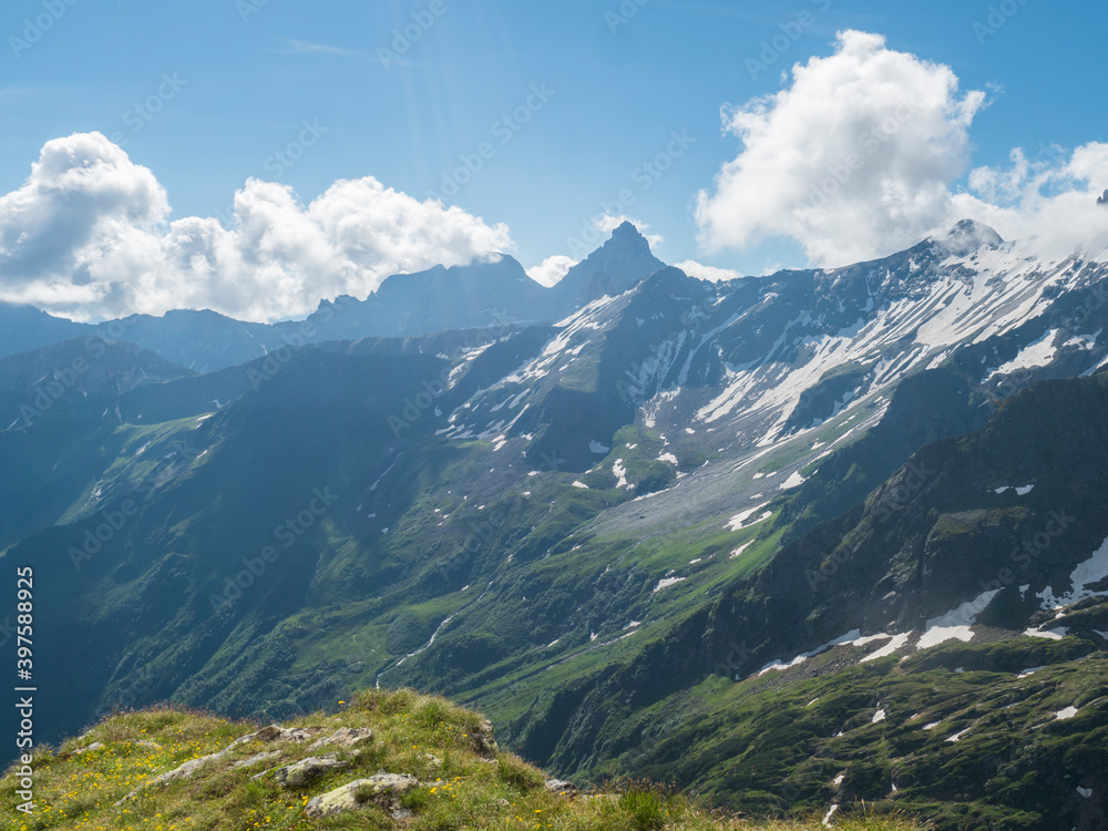 view on snow-capped moutains and green valley with winding spring stream at Stubai hiking trail, Stubai Hohenweg, Alpine landscape of Tyrol, Stubai Alps, Austria. Summer blue sky