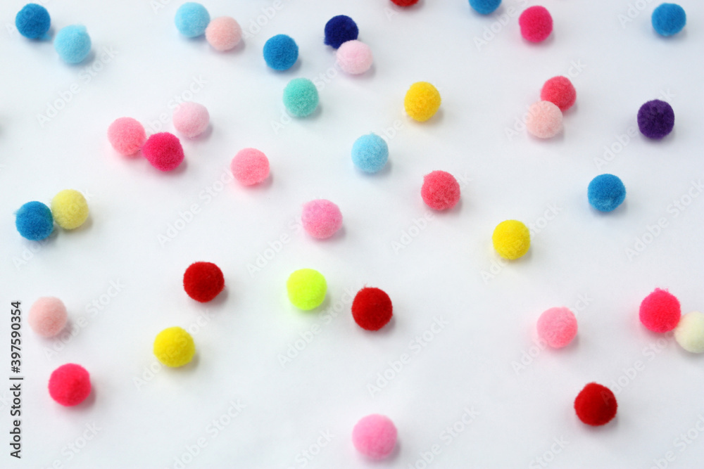 Small fur balls randomly lie on a white background. Pompoms for needlework and handmade. Small fur balls randomly lie on a white background. Pompoms for needlework and handmade.