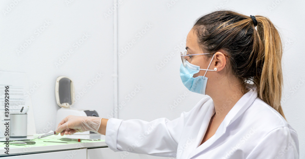 A young chiropodist taking her tools from the work table while doing a chiropractic. A doctor taking her medical tools. A young chiropodist taking her tools from the work table while doing a chiropractic. A doctor taking her medical tools.