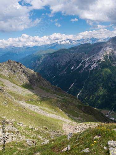 view from Pramarnspitze saddle on Gschnitztal Valley and snow-capped moutain panorama at Stubai hiking trail, Stubai Hohenweg, Alpine landscape of Tyrol Alps, Austria. Summer blue sky, white clouds