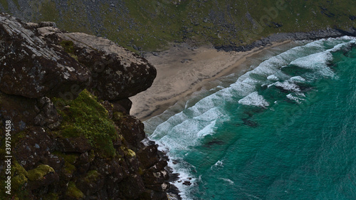 Stunning aerial view of popular sand beach Kvalvika with turquoise colored water and wild surf located on the coast of Moskenesøya island, Lofoten, Norway with rocks in foreground.