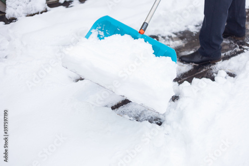 A man cleans the snow with a big blue shovel