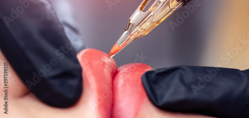 Bild auf Leinwand Banner Process woman applying permanent tattoo makeup on lips in beautician salo