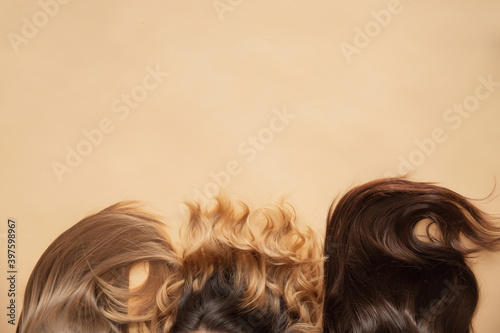 Different type of hair blonde, brunette, wavy on beige background, top view. Spa concept for root and tip care photo