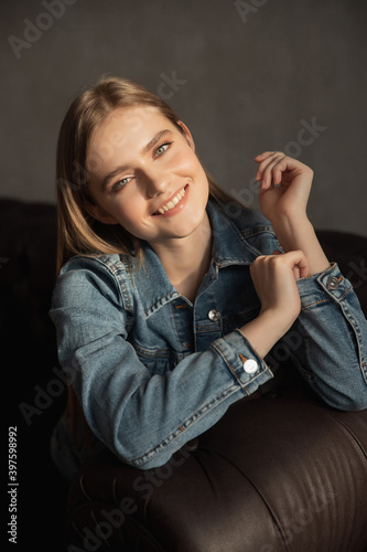 Portrait of young blonde woman with green eyes in denim jacket on dark background. Hand skin care concept in frost