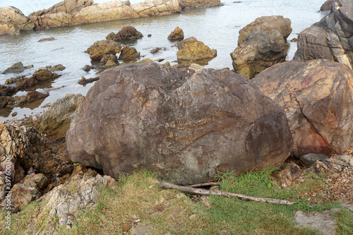 A large sandstone sedimentary rock located by the sea